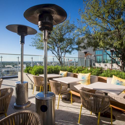 A sunny seaside caf&eacute; with palm trees, wicker chairs, and pastel umbrellas; people dine near the water, boats in the distance.