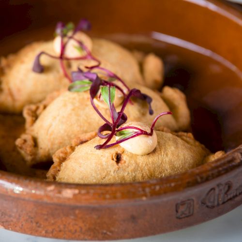 Cinnamon-sugar topped baked apple or cookie in a rich sauce, served in a ramekin with almonds, raisins, and a glossy caramel glaze.